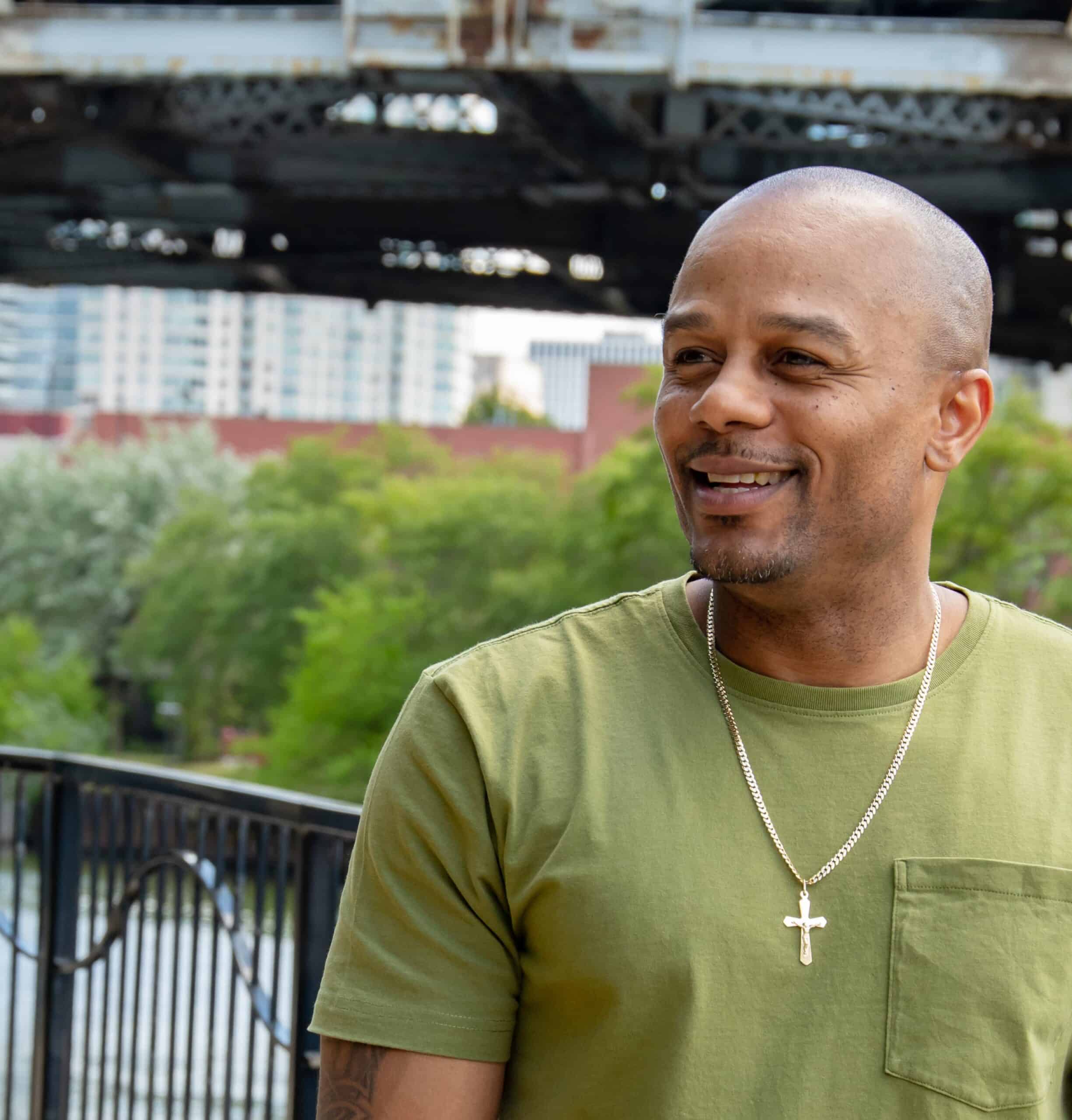 Black man smiling and looking off to the side, wearing a t-shirt